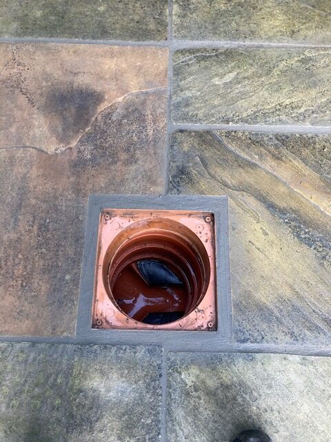 Open access point to an underground drain pipe showing a clean and repaired drainage system